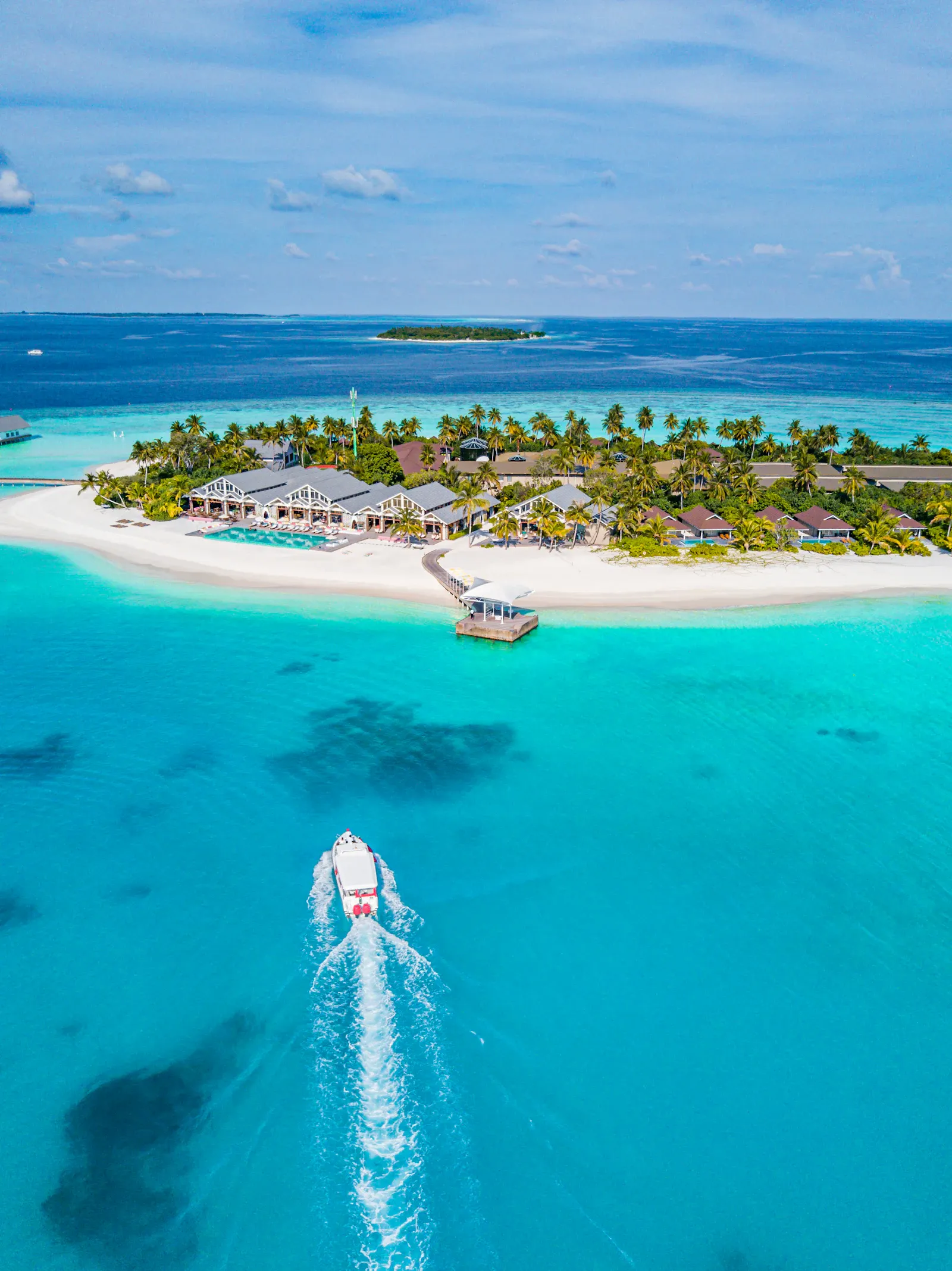 A boat crossing turquoise water toward a small island