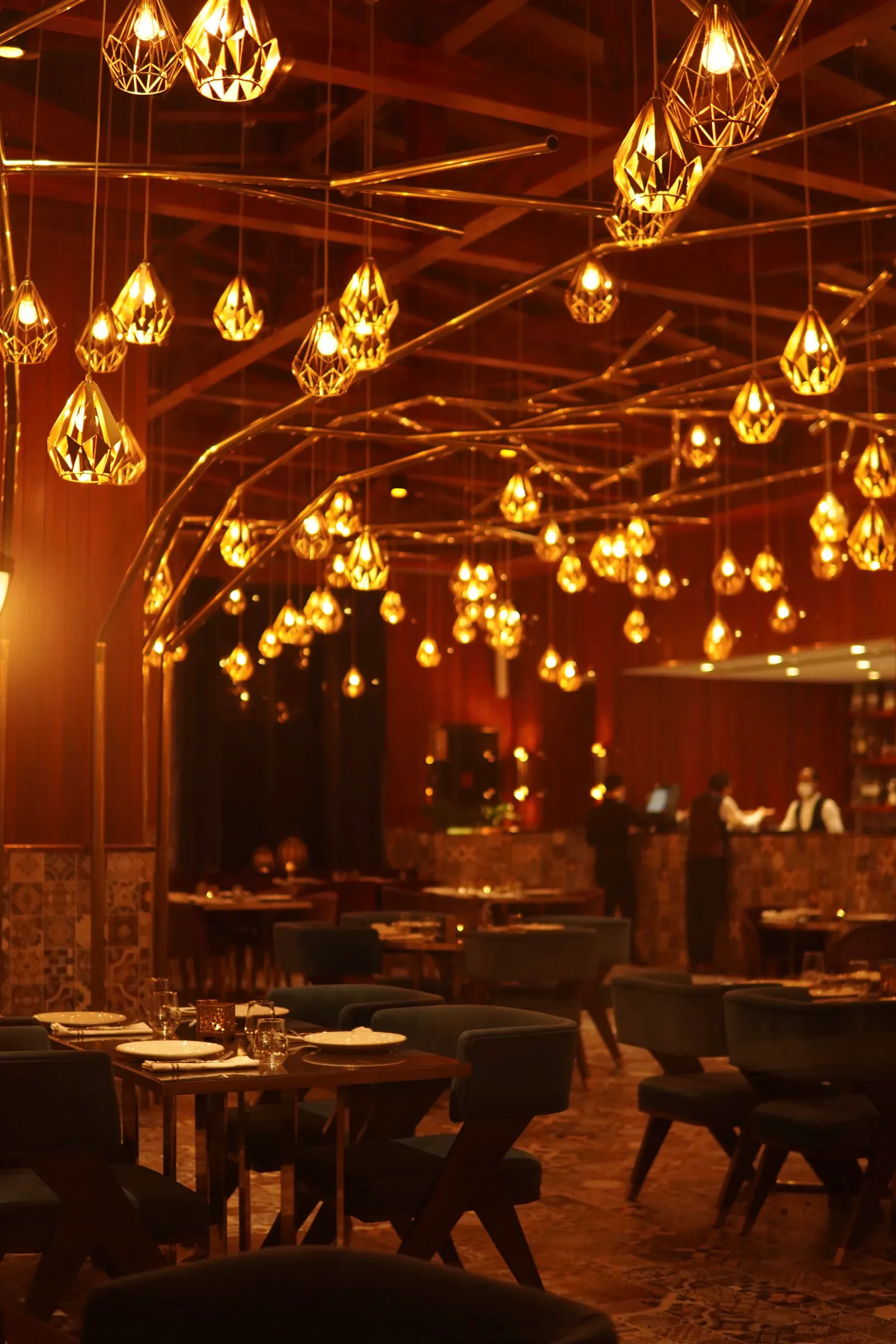 The dining room in the evening, lit by clusters of warm lamps