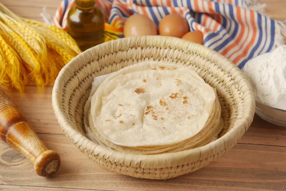 Warm roshi flatbread stacked in a woven basket